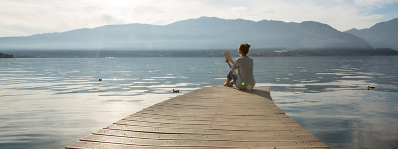 Women reading a book while sitting on a dock